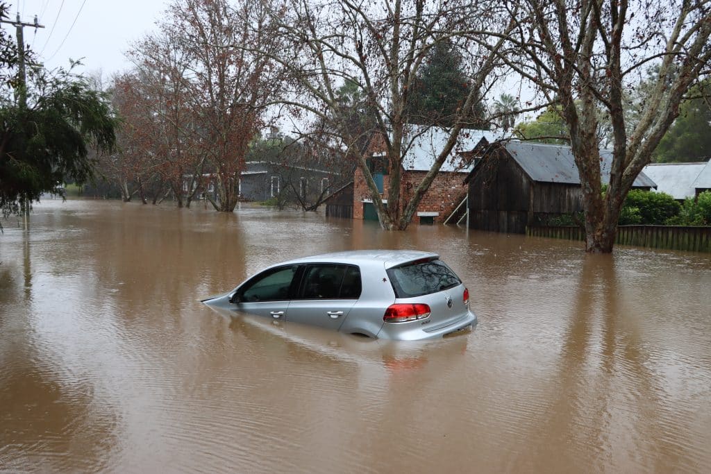 A car half submerged in high flood waters.