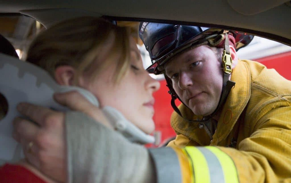 A firefighter gives medical attention to a woman injured in a car accident.
