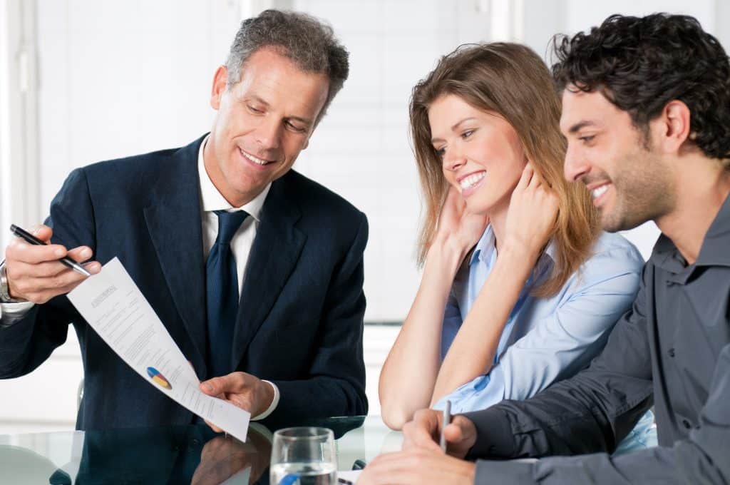 Insurance agent discussing coverage with young couple.
